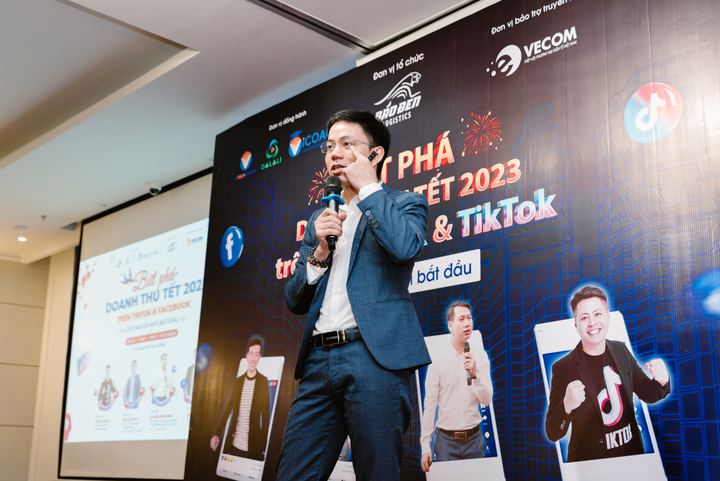 Diễn giả cầm micro trên sân khấu có phông nền sự kiện