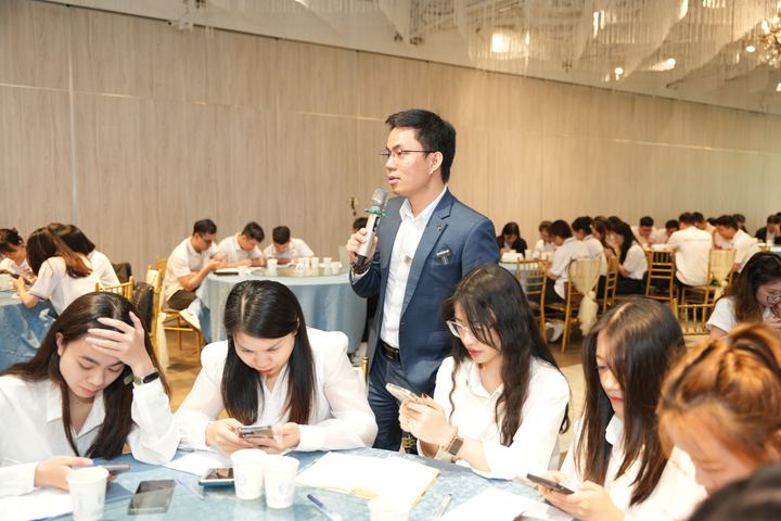 Diễn giả cầm micro trao đổi giữa hội trường đông người