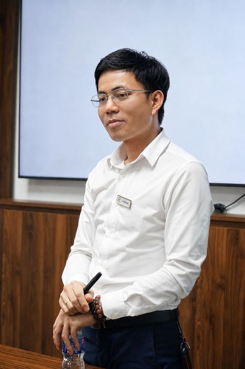 Diễn giả đứng cạnh màn chiếu trong phòng đào tạo