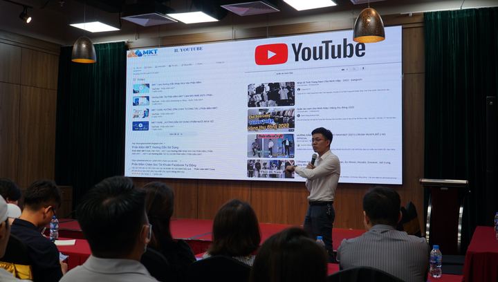 Diễn giả thuyết trình bên màn hình chiếu lớn
