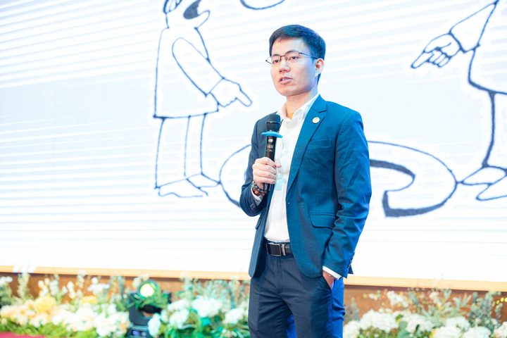 Diễn giả cầm micro trên sân khấu hội thảo