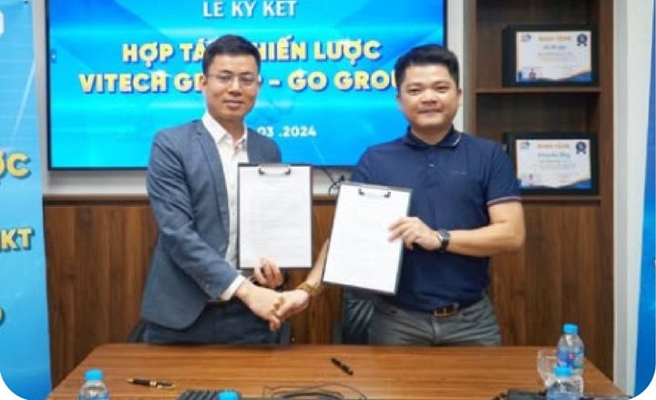 Hai đại diện bắt tay, cầm văn bản trong lễ ký kết